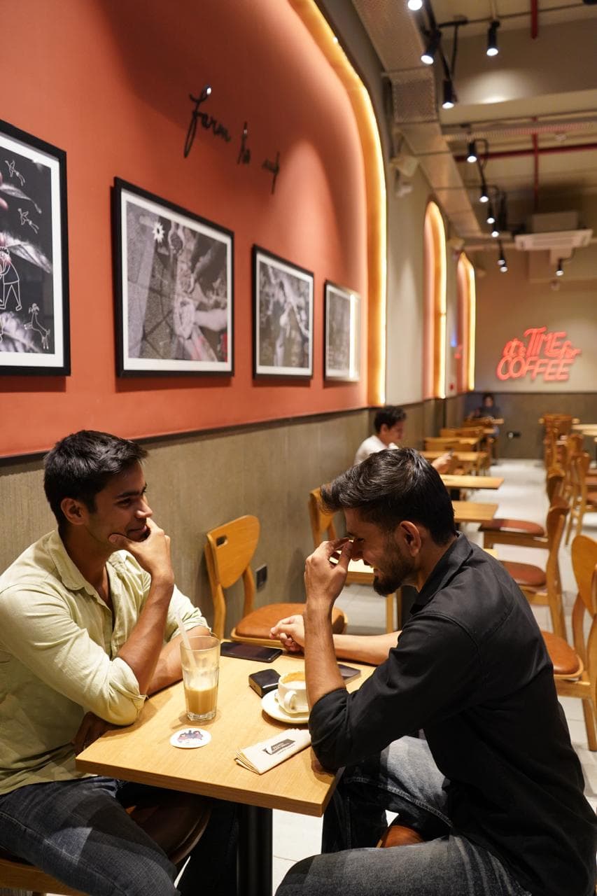 Two people talking over coffee and dessert at a warmly lit cafe table